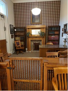 alcove with a stately plaid wall, an unused fireplace, wooden desks and chairs
