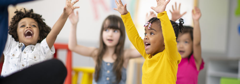 Group of smiling children holding hands up
