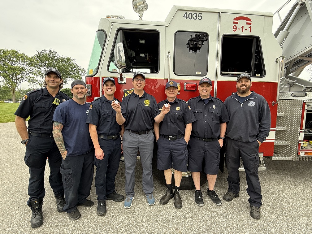 Windsor fire fighters in front of fire truck holding two golf balls