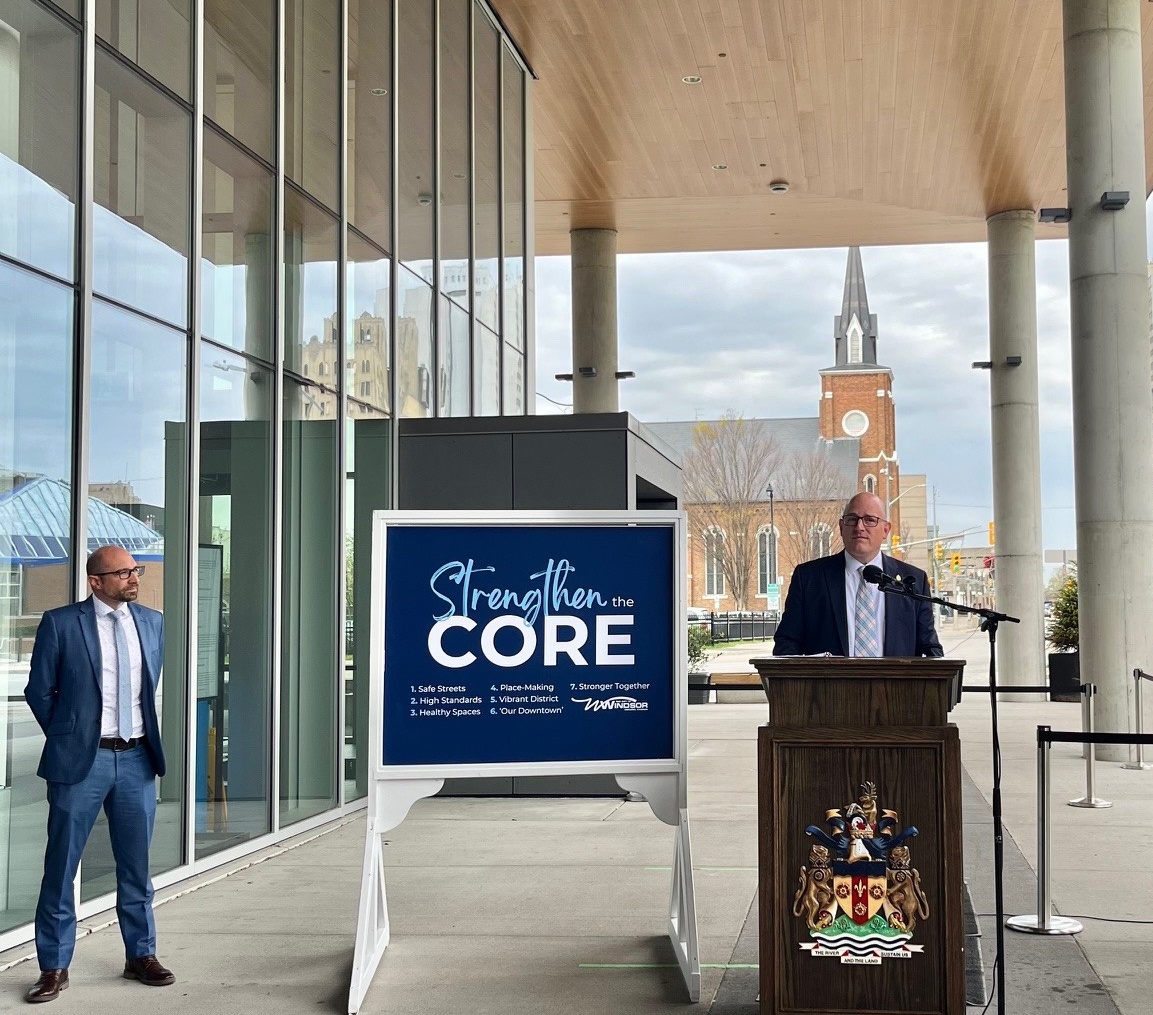 Strengthen the Core H4 media conference Mayor Dilkens at a podium and Commissioner of Human and Health Services Andrew Daher flanking a sign that reads, Strengthen the Core, 1, Safe Streets; 2, High Standards; 3, Healthy Spaces; 4, Place-Making; 5, Vibrant District; 6, Our Downtown; 7, Stronger Together
