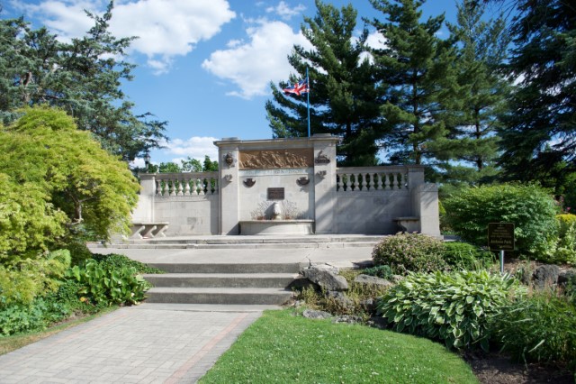 Limestone and bronze monument with fountain in a park.