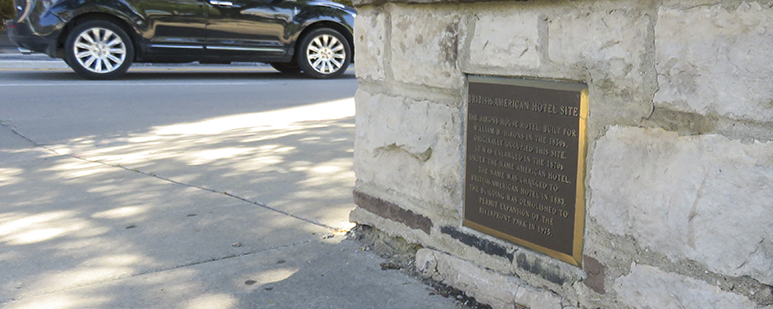 Small, ground level, bronze plaque by a road in a park.