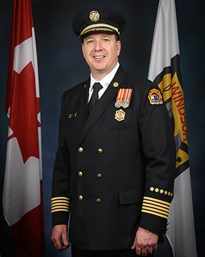 Fire Chief James Waffle formal portrait Fire Chief James Waffle in formal uniform flanked by flags of Canada and Windsor Fire & Rescue Services